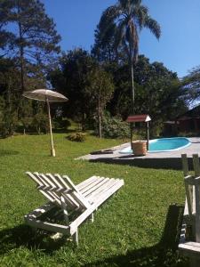 two lawn chairs and an umbrella next to a swimming pool at Sítio Gacied in Suzano