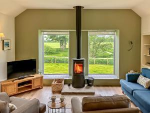 a living room with a wood stove in the middle at Kingfisher Cottage in Kirkton of Airlie
