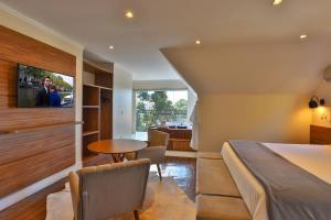 - une chambre avec un lit, une table et une télévision dans l'établissement Ti Voglio Bene, à Campos do Jordão