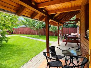 eine Terrasse mit Tischen und Stühlen unter einer hölzernen Pergola in der Unterkunft Babett Vendégház in Zánka