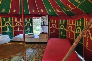 a red and green tent with a bed in it at Dommaine hadda in Khemisset