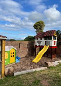 a playground with a house and a slide at Eden Garden Luxury Lodges in Llangain