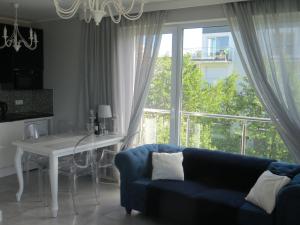 a living room with a blue couch and a table and a window at Lighthouse Apartment in Gąski