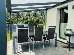 a patio with a table and chairs and a grill at Cosy holiday home HELMA directly at the Baltic Sea in Zierow