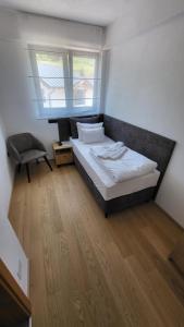 a bedroom with a bed and a chair and a window at Janjska Kuća in Šipovo