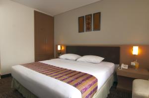 una camera d'albergo con un grande letto bianco con due cuscini di Cipta Hotel Wahid Hasyim a Giacarta