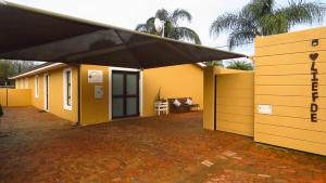 Casa amarilla con techo negro y patio en Sonvanger, en Paarl