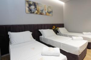 a room with three beds and a painting on the wall at Bee Hotel in Vlorë