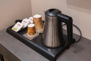a tea kettle on a black shelf with candles at Bee Hotel in Vlorë