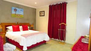1 dormitorio con 1 cama grande y cortinas rojas en Sonvanger, en Paarl