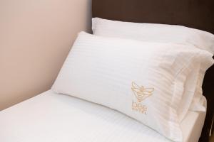 a bed with white pillows with a rosie sign on it at Bee Hotel in Vlorë
