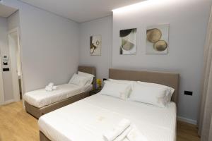 twee bedden in een kleine kamer met witte muren bij Bee Hotel in Vlorë