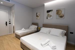 a bedroom with two beds with white sheets and white pillows at Bee Hotel in Vlorë