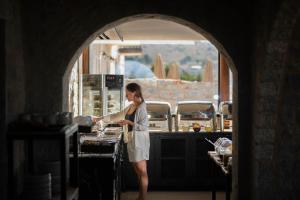 a woman standing in a kitchen preparing food at Petra & Fos Boutique Hotel & Spa in Neo Itilo