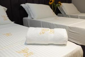 a group of three beds with towels on them at Bee Hotel in Vlorë