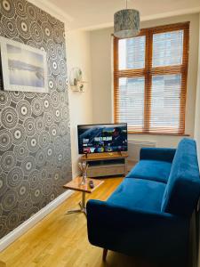 sala de estar con sofá azul y TV en 2 bedroom flat in heart of Luton Town and Station en Luton