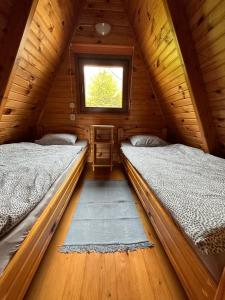 two beds in a wooden cabin with a window at Domek na górze z pięknym widokiem in Bukowiec