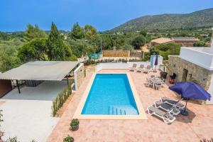 a pool with chairs and an umbrella on a house at Villa La Sella by Rock Rentals in Muntanya la Sella