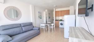 a living room with a blue couch and a kitchen at Estudio Jávea Park Arenal in Jávea