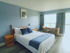 a bedroom with a bed and a table and a window at Glenghorm Beach Resort in Ingonish