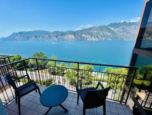 a balcony with chairs and a view of the water at Hotel Villa Carmen in Malcesine