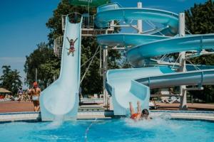 a person falling off a water slide in a pool at Hiška Amoris K117 Terme Banovci, 2 kopalni karti gratis in Veržej