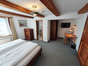 a bedroom with a bed and a desk and a television at Adler Hotel in Appenzell