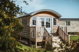 a wooden cabin with a porch and a white door at Hornington Manor Luxury Shepherd Huts in York