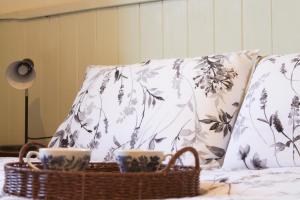 two cups on a bed with two pillows and a basket at Splendid Wren Cottage in Deeside