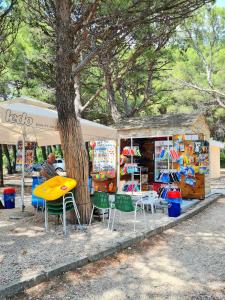 a table and chairs in front of a store with a tree at Natua Apartment in Krvavica
