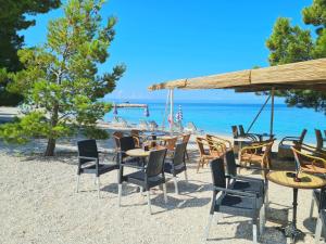 a group of chairs and tables on the beach at Natua Apartment in Krvavica