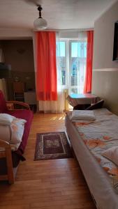 レバルにあるNoclegi U Krystynyのベッドルーム1室(ベッド2台付)、赤いカーテン付きの窓が備わります。