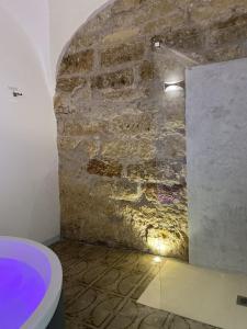 a bathroom with a stone wall and a toilet at Settegrana Suite con vasca idromassaggio in Cinisi