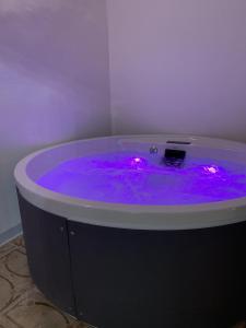 Settegrana Suite con vasca idromassaggio في شينيسي: حوض استحمام أرجواني مع أضواء في الغرفة