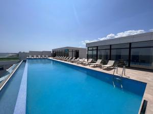 a large swimming pool with lounge chairs on a building at Summer Briva by Infinity -Mamaia Nord-Sea View-Private Parking in Mamaia Sat/Năvodari