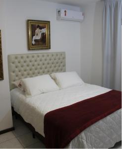 um quarto com uma cama grande com lençóis brancos e uma fotografia em Casa MAgdeburg II - Central e completa em Pomerode