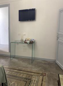 a glass table with a television on a white wall at Settegrana Suite con vasca idromassaggio in Cinisi