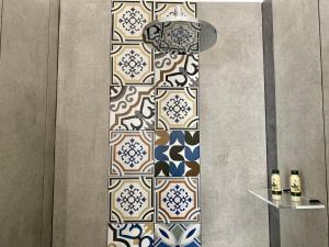 uma casa de banho com uma parede com um padrão de azulejos em D'Angiò Rooms-Manfredi Homes&Villas em Manfredonia