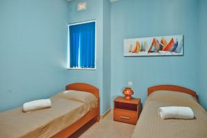 2 Betten in einem Zimmer mit blauen Wänden und einem Fenster in der Unterkunft Gozo Spacious Apartment with Large Communal Pool in Qala