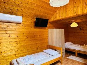 a wooden room with two beds and a tv at Babett Vendégház in Zánka