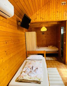ein Schlafzimmer mit einem Bett in einem Holzzimmer in der Unterkunft Babett Vendégház in Zánka