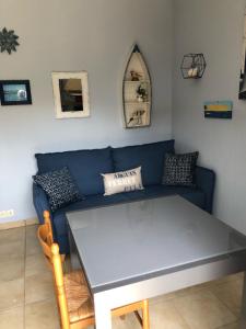uma sala de estar com um sofá azul e uma mesa em Les Alizés em Le Teich