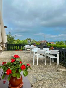 um pátio com mesas brancas e flores vermelhas em Agroturismo Kostegi em Urnieta