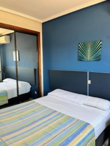 a blue room with two beds and a mirror at Apartamentos Olano C.B. in Madrid