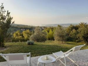 Deux chaises blanches et une table sur un champ dans l'établissement Apartment Nona Ervina, à Koper