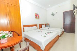 クイニョンにあるCiao Hồng Phúc Hotelのベッド2台とテーブルが備わる小さな客室です。
