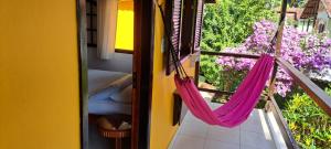 Recanto das Flores Lofts - Ilha Grande Rj في أبراو: غرفة مع أرجوحة على شرفة مع زهور