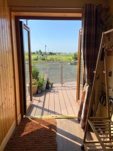 an open door to a patio with a view of the water at The Stable - NC500 in Wick