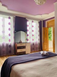 1 dormitorio con 1 cama con espejo y paredes moradas en Mira House en Martvili