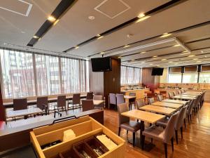 Dormy Inn Himeji Natural Hot Spring في هيميجي: غرفة طعام كبيرة مع طاولات وكراسي ونوافذ